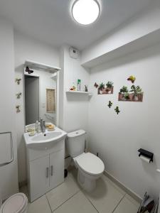 a white bathroom with a toilet and a sink at Une petite chambre jardin in Dijon +9 photos