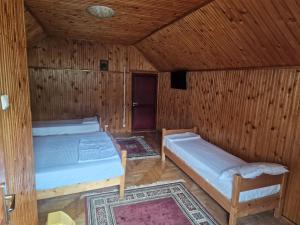 two beds in a room with wooden walls at Casa Ursilor in Predeal