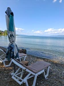 two lounge chairs and an umbrella on a beach at Gardenhouse in Mëmëlisht