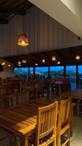 a dining room with wooden tables and chairs and lights at Flor do Umari Eco Hotel e Eventos in Serra de São Bento