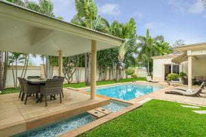 a backyard with a table and chairs and a swimming pool at Luxury Pool Villa 3BR 6-8 persons in Nong Prue