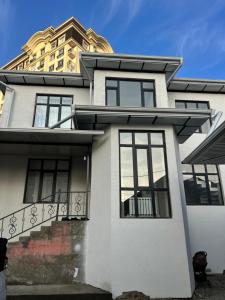 a white house with a balcony and a building at Royal hostel in Osh