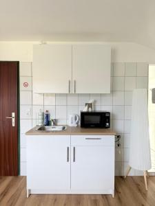 a kitchen with white cabinets and a sink and a microwave at Sleep & Go Höchst in Höchst