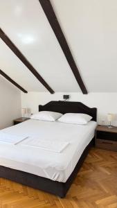 a bedroom with a large white bed with two tables at Apartmani Kovačević in Kotor