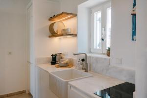 a white kitchen with a sink and a window at Casa Elia in Sarakíniko +25 photos