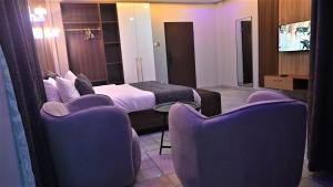 a hotel room with a bed and two chairs at Andysilk Resort International in Ozu Abam