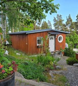 a small wooden shed with a door in a garden at Gäststugan in Åkersberga