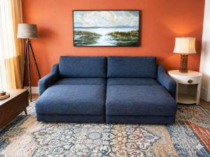 a blue couch in a living room with an orange wall at Renovated Oceanfront 1BR by Skywheel Yachtsman 400 in Myrtle Beach