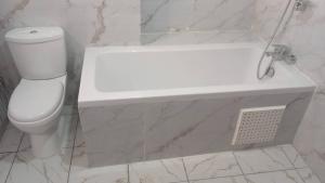 a white bathroom with a toilet and a sink at Le Conviviall in Yaoundé