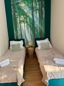 two beds in a room with a painting on the wall at Leśna Przystań in Pojezierze