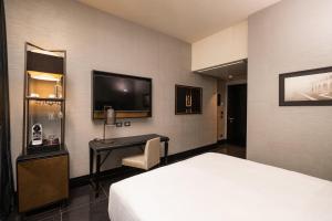 a hotel room with a bed and a desk and a tv at The Venice Times Hotel, Vignette Collection by IHG in Venice