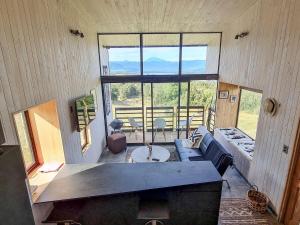 a living room with a couch and a large window at Spectacular tiny house in an unforgettable setting in Ñilque