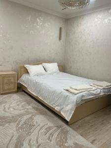 a bedroom with a bed with white sheets and a chandelier at Royal hostel in Osh