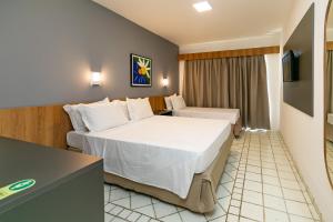 a hotel room with a large bed and a television at El Aram Beach Cabo - All Inclusive in Cabo de Santo Agostinho