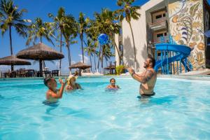 a man and children playing in the swimming pool at a resort at El Aram Beach Cabo - All Inclusive in Cabo de Santo Agostinho