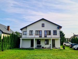 a white house with black windows and a yard at Villa Bianca in Mikołajki