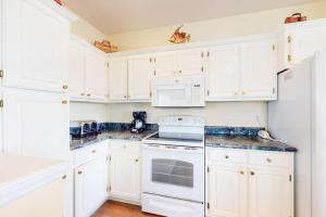 a white kitchen with white appliances and white cabinets at Charming ocean-view gem with a pool deck washer dryer & central AC in St. George Island