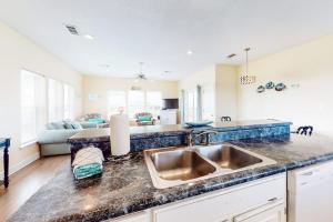 a kitchen with a sink and a living room at Charming ocean-view gem with a pool deck washer dryer & central AC in St. George Island