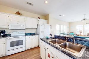 a kitchen with white cabinets and a sink at Charming ocean-view gem with a pool deck washer dryer & central AC in St. George Island +16 photos