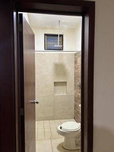 a bathroom with a toilet in a room with a window at Departamento Rousse in Tequila
