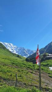 a red and white flag on a pole in a field at Sarag in Ushguli