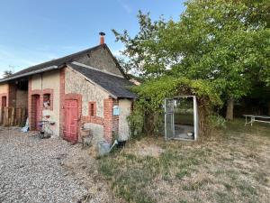 an old brick building with a door in a yard at Maison solognotte in Sainte-Montaine