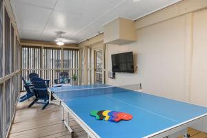 a blue ping pong table in a room with chairs at 1128 Summerwind Cottage in Seabrook Island