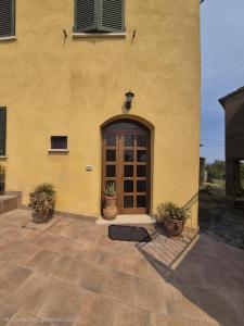 a yellow building with a door and two potted plants at La casina dei nonni in Sinalunga