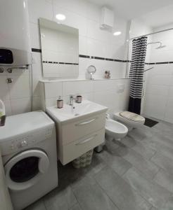 a white bathroom with a washing machine and a toilet at Idila in Izola