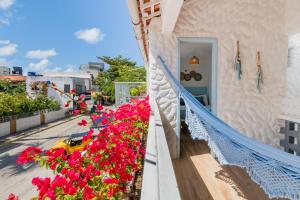 a balcony with red flowers on a building at Pousada Vila DuJu in Porto De Galinhas