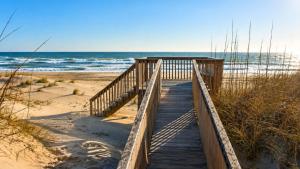 a wooden boardwalk leading to a beach with the ocean at Rio Rodanthe Lazy River Kiddie Pool Oceanfront Elevator in Rodanthe