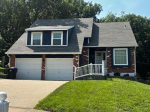 a brick house with a white gate and a driveway at The Welcome Home in Topeka