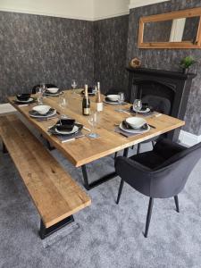 a wooden table with plates and wine glasses on it at Flown The Nest in Bridlington