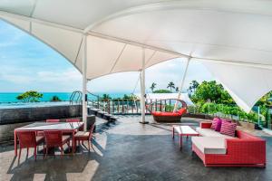 an outdoor patio with tables and chairs and a view of the ocean at Le Meridien Bali Jimbaran in Jimbaran