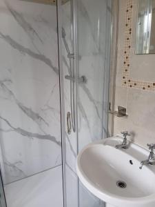 a white bathroom with a sink and a shower at Flown The Nest in Bridlington +23 photos