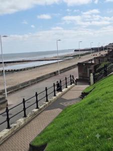 a fence next to a beach with a pier at Flown The Nest in Bridlington