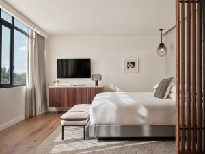 a white bedroom with a bed and a tv at Kimpton El Castelar Polanco by IHG in Mexico City