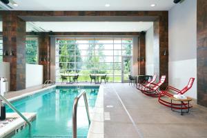 a pool with red chairs and a table in a room at Archer Hotel Seattle/Redmond in Redmond