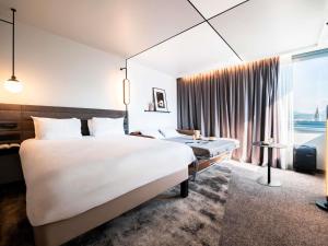 a hotel room with a large bed and a large window at Novotel Grenoble Centre in Grenoble