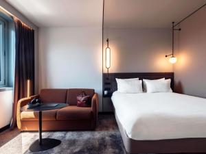 a hotel room with a bed and a couch at Novotel Grenoble Centre in Grenoble