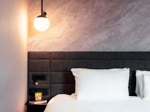 a bedroom with a white bed with a black headboard at Novotel Grenoble Centre in Grenoble