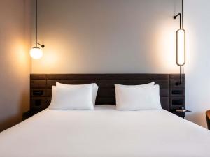 two white pillows sitting on a bed with two lights at Novotel Grenoble Centre in Grenoble +113 photos