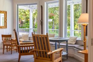 a living room with a table and chairs and windows at Auberge Les Sources in La Malbaie