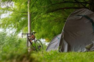 a bike parked next to a tent in the grass at Camp & Hostel Maltakva in Poti