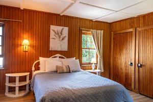 a bedroom with a bed with wooden walls and a window at Auberge Les Sources in La Malbaie