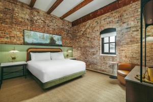 a bedroom with a bed and a brick wall at The Hotel Monroe, Tapestry Collection By Hilton in Monroe +32 photos