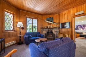 a living room with two blue chairs and a fireplace at Auberge Les Sources in La Malbaie
