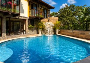 a swimming pool with a waterfall in front of a house at Hotel Casa Encantada in Penedo