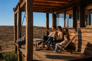 a family sitting on the porch of a cabin at Valle de la Luna in Tandil