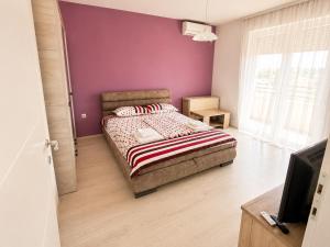 a bedroom with a bed and a purple wall at Harmony Relax in Paraćin